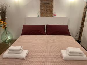 Una cama con almohadas rojas y toallas. en CASA CIMELLA, un nido nel cuore del porto antico cod CITRA 010025-LT-2629 en Génova