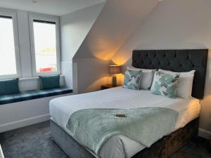 a bedroom with a bed and a couch and windows at Killorn Guest House in Oban