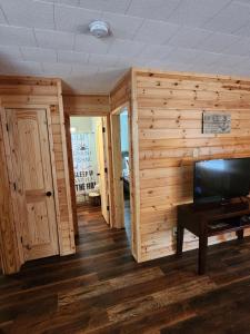 a living room with wooden walls and a flat screen tv at Southern Comfort Inn & Resort in Fairfield Bay