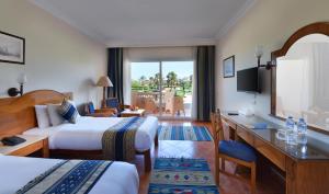 a hotel room with two beds and a desk at Bliss Nada Beach Resort in Coraya Bay