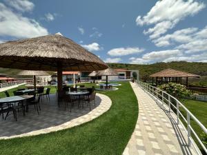 a patio with tables and umbrellas on the grass at Hotel Aconchego do Velho Chico in Piranhas