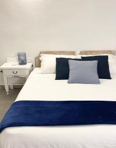 a large bed with blue and white pillows and a desk at Cala Reale Rooms Marinella in Marinella