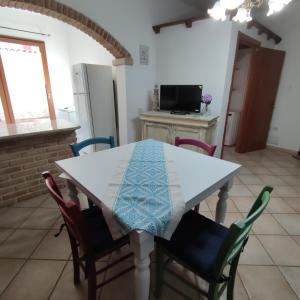 una cocina con una mesa blanca con sillas y una barra en La Casa di Paolo, en Terralba