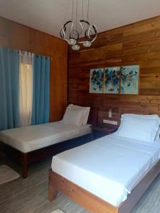 two beds in a room with wooden walls at Theresa's Pension House in San Vicente