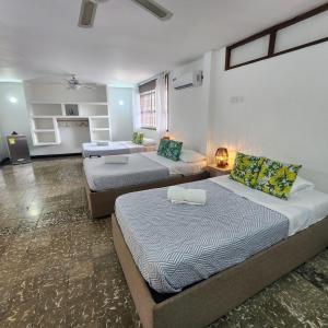 a bedroom with two beds and a living room at Casa Matuna - Cartagena in Cartagena de Indias