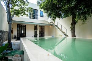 a swimming pool in front of a house with trees at Casa Tsapot in Mérida