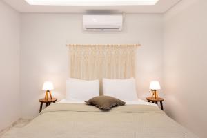 a bedroom with a bed with white walls and two lamps at Dia Urla in Urla