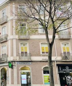 um edifício com uma árvore em frente em RSRC Central & Bright 1BR apartment em Lisboa