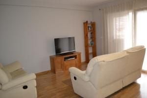 a living room with two chairs and a flat screen tv at Vivienda Falda del Monsacro in Santa Eulalia de Morcín