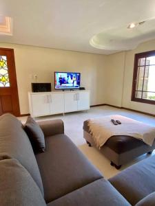 ein Wohnzimmer mit einem Sofa und einem Flachbild-TV in der Unterkunft Excelente casa na Praia do Cassino, RS in Rio Grande