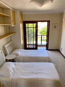 1 Schlafzimmer mit 2 Betten, einem Tisch und einem Fenster in der Unterkunft Excelente casa na Praia do Cassino, RS in Rio Grande