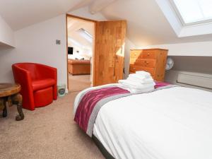 a bedroom with a bed and a red chair at The Parlour in Frodsham