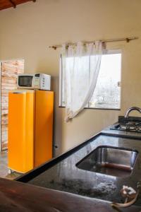 a kitchen with a sink and a yellow refrigerator at Casa Da Cléo Carrancas in Carrancas