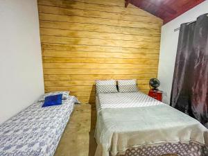 a bedroom with two beds and a wooden wall at Casa Da Cléo Carrancas in Carrancas