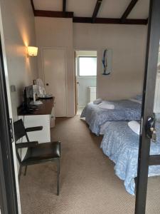 Zimmer mit 2 Betten, einem Schreibtisch und einem Stuhl in der Unterkunft Pinelodge in Opua