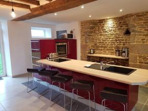 a kitchen with a counter with a sink and red cabinets at les saisonnières 18 personnes avec piscine in Céaux