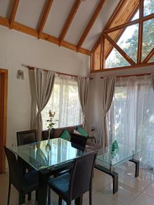 a dining room with a glass table and chairs at Cabaña El Tiempo Es Arte in San José de Maipo