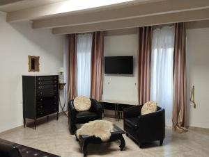 een woonkamer met 2 stoelen en een flatscreen-tv bij Affittacamere Vicino al Porto in Porto Torres