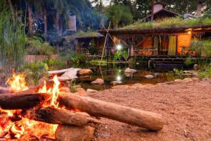 uma fogueira em frente a uma cabana de madeira em Recanto Ecológico em São Gabriel