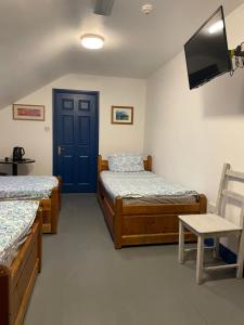 Habitación con 2 camas, TV y puerta. en Coastguard Lodge Hostel at Tigh TP en Dingle