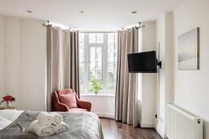 - une chambre avec un lit, une chaise et une fenêtre dans l'établissement 6-bedroom LUX House next to Hyde Park &Marble Arch, à Londres