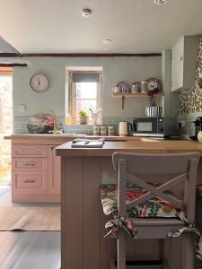 eine Küche mit rosa Schränken und einer Arbeitsplatte in der Unterkunft Rowan Cottage in Cromford