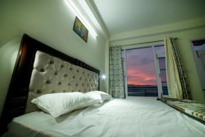een slaapkamer met een groot bed en een groot raam bij Mom Blessing Homestay in Shimla