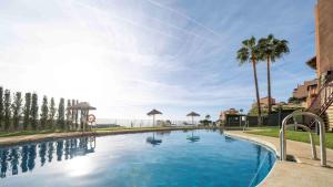 uma grande piscina com palmeiras ao fundo em Casa Jasmina Calahonda with seaview 2 bed 2 bath em Sitio de Calahonda