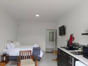 a bedroom with a bed and a desk with a television at Guest Suite 2 at Rustic Dune in Jeffreys Bay