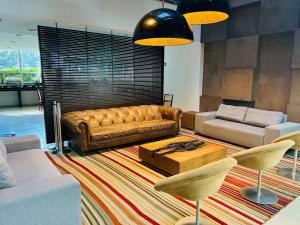 uma sala de estar com um sofá de couro castanho e cadeiras em Naoum Hotel em Brasília