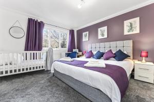 a bedroom with a large bed and a crib at The Woodlands, shortstay, ideal for families, relocation, contractors, travel stay in Horley