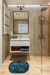 een badkamer met een wastafel en een douche met een spiegel bij VipWarsawApartments pl Sienna 65 in Warschau