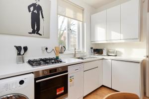 kuchnia z białymi szafkami i piekarnikiem w obiekcie The Putney Hideout - Bright 1BDR Flat w Londynie