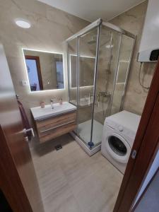 a bathroom with a shower and a sink and a washing machine at Royal apartment Salona in Klis
