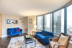 uma sala de estar com mobiliário azul e janelas grandes em Captivating Apartment with Pier Views, Pool and Gym em Chicago