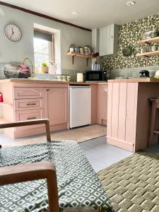 eine Küche mit rosa Schränken und einer Uhr an der Wand in der Unterkunft Rowan Cottage in Cromford