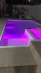 una piscina con iluminación púrpura en una habitación en Casa Rústica, piscina com aquecimento solar e SPA, en Itapoa