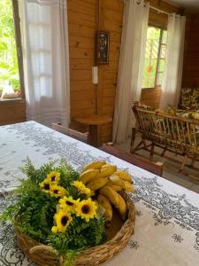 una cesta de plátanos y flores sobre una mesa en Casa Rústica, piscina com aquecimento solar e SPA, en Itapoa