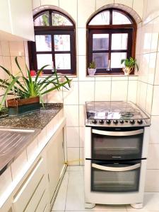 a kitchen with a stove and two windows at Casa 146 - SP Expo, Metrô, Congonhas in Sao Paulo