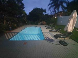 uma piscina vazia com guarda-sol e cadeiras em Modern Luxury Beach House em Ballito