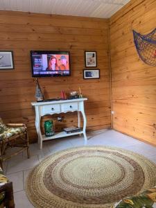 sala de estar con TV en una pared de madera en Casa Rústica, piscina com aquecimento solar e SPA, en Itapoa