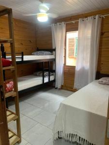 1 dormitorio con 2 literas y ventana en Casa Rústica, piscina com aquecimento solar e SPA, en Itapoa