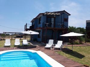 una casa con piscina, sillas y sombrillas en Aroma de mar, en Sauce de Portezuelo