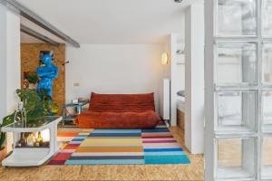 een woonkamer met een bank en een kleurrijk tapijt bij Cosy art studio near station with bikes and garden in Gent