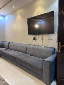 un sofá con TV de pantalla plana en la pared en استراحة وشاليه وقاعة السلطانه رجال en Al-Salam