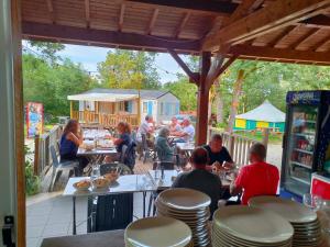 L'ERABLE - CABANE INSOLITE et COCOONING 2 personnes - CAMPING LE BEL AIR في Limogne-en-Quercy: مجموعة من الناس يجلسون على الطاولات في المطعم +4 صور
