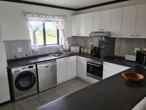 a kitchen with white cabinets and a washer and dryer at Plett Sunrise:) in Plettenberg Bay