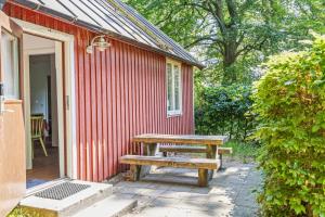 un banco de madera sentado fuera de un edificio rojo en Fiskestugan – Country side cottage by lake, en Sjöbo
