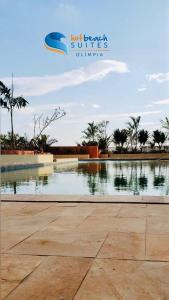 une piscine d'eau dans un parc planté de palmiers dans l'établissement Hot Beach Suites - Apartamento, à Olímpia