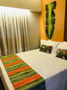 - une chambre avec un lit et une couverture colorée dans l'établissement Hot Beach Suites - Apartamento, à Olímpia